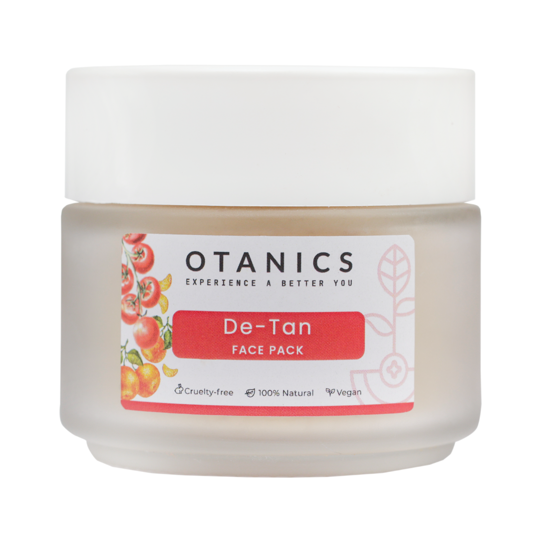 Image of Otanics De-Tan Face Pack jar with a white lid and a clear label. The label reads 'Otanics De-Tan Face Pack' with a red background and illustrations of tomatoes. The jar is labeled as cruelty-free, 100% natural, and vegan. The product is placed on a clean background, showcasing the packaging of the face pack.