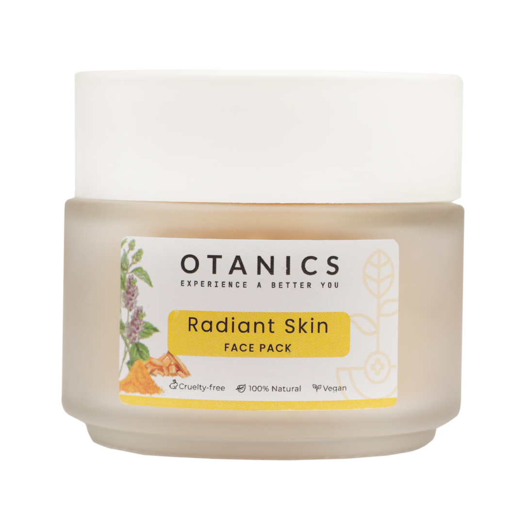 Image of Otanics Radiant Skin Face Pack jar with a white lid and a clear label. The label reads 'Otanics Radiant Skin Face Pack' with a yellow background, featuring botanical illustrations and turmeric. The jar is placed on a plain background, showcasing the product packaging. The label also indicates the product is cruelty-free, 100% natural, and vegan, and suitable for all skin types.