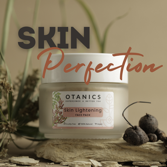 Image of Otanics Skin Lightening Face Pack jar with a white lid and a clear label. The label reads 'Otanics Skin Lightening Face Pack' with a soft pink background, and includes icons indicating the product is cruelty-free, 100% natural, and vegan. The jar is placed on a textured surface, surrounded by natural elements, with the bold text 'SKIN Perfection' displayed above.